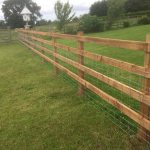 Post and rail fencing and gate in a empty field. The perfect commercial fencing for housing livestock.