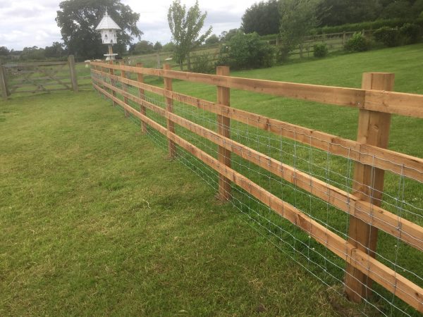 Post and rail fencing and gate in a empty field. The perfect commercial fencing for housing livestock.