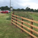 Wooden post and rail fencing surrounding a field.