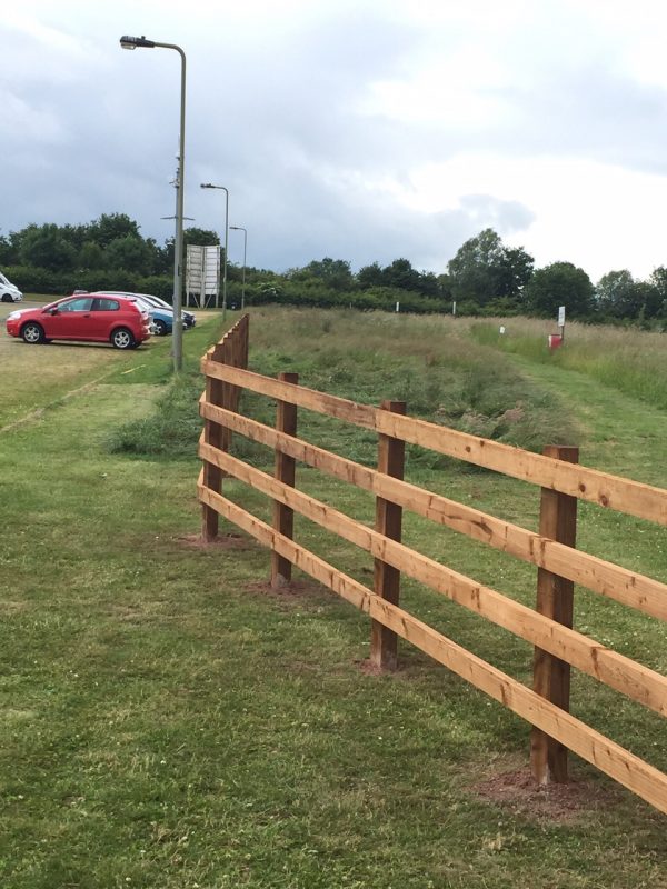 Wooden post and rail fencing surrounding a field.