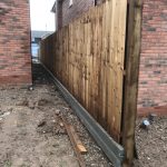 Newly assembled wooden garden fencing between two houses under construction.