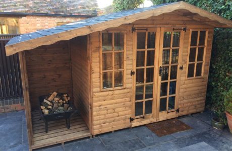 Made to measure garden shed standing in a yard beside a wall of ivory. This bespoke shed has glass windows and doors.