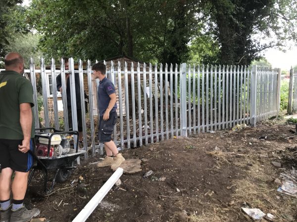 Steel commercial fencing being installed by three Hodges & Lawrence staff members in an outdoor space in Birmingham.