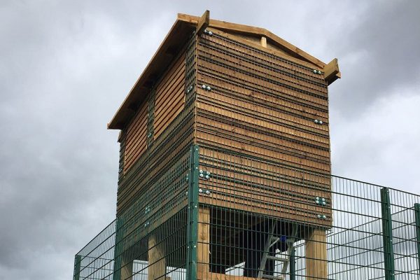 A fully structured commercial shed surrounded by a green steel commercial fence.