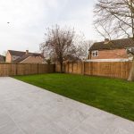 A large garden surrounded by feather edged wooden fencing.