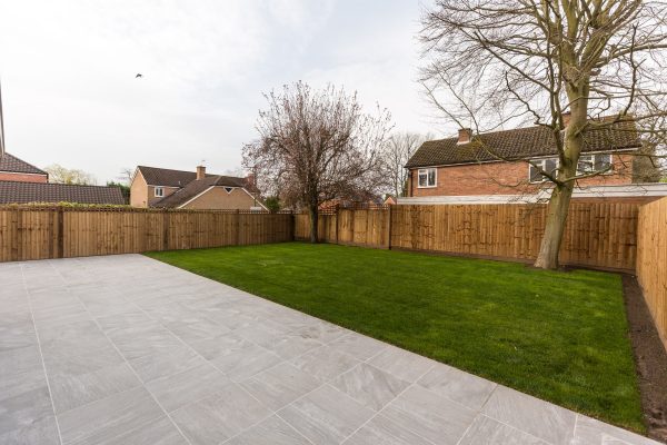 A large garden surrounded by feather edged wooden fencing.