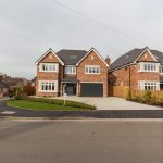 A new build housing estate, two houses side by side with a paling fence in between.