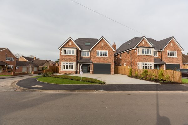 A new build housing estate, two houses side by side with a paling fence in between.