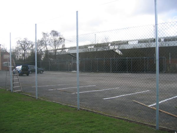 Chan link fencing. The commercial fence surrounds a car park containing two parked cars.