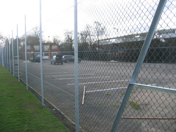 Chain linking fence surrounding a car park. This commercial fence provides security to the cars inside.