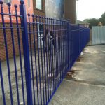Blue bespoke railings surround a commercial or industrial building.
