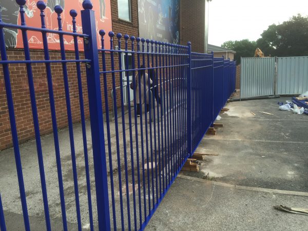 Blue bespoke railings surround a commercial or industrial building.