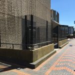Black double mesh fencing surrounding the entrance to a commercial building.