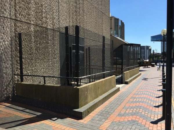 Black double mesh fencing surrounding the entrance to a commercial building.