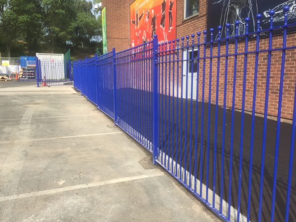 Blue bespoke railings stand in front of a commercial building.