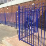 Blue bespoke railings surrounds a commercial area.