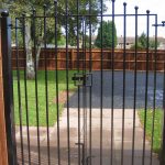 Black vertical bar steel gates. Locked and securing a garden.