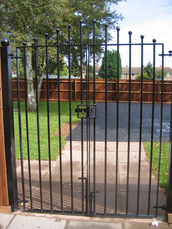 Black vertical bar steel gates. Locked and securing a garden.