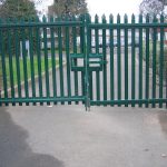 Green steel palisade gates stand in front of an school. These commercial gates provide security for the school.
