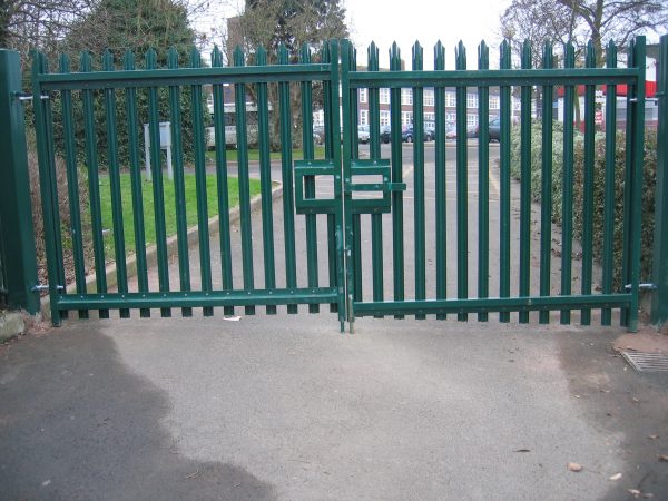 Green steel palisade gates stand in front of an school. These commercial gates provide security for the school.