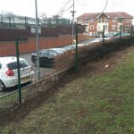 Mesh fencing panels standing in front of parked cars. These commercial gates offer security for private areas.