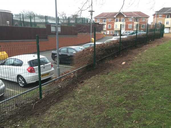 Mesh fencing panels standing in front of parked cars. These commercial gates offer security for private areas.