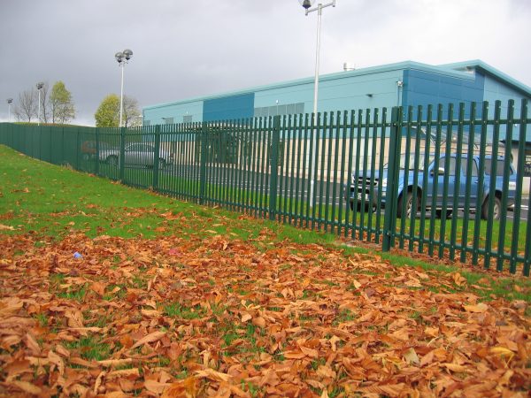 Green steel palisade fencing installed around a car park. Commercial fencing securely protects cars inside the car park.