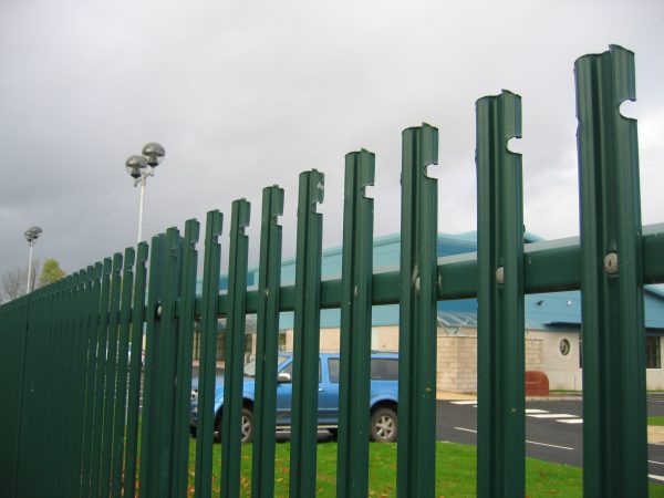 Green steel palisade fencing. This commercial fence is providing security for cars inside a car park.