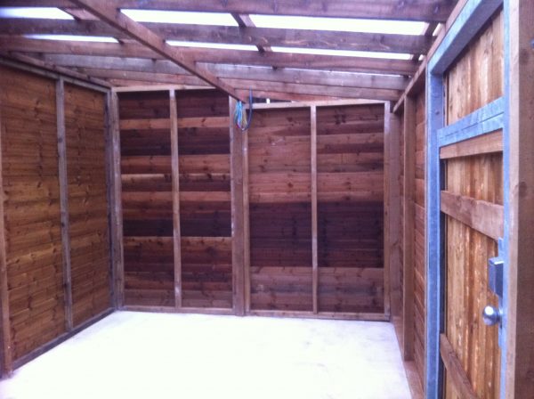 Inside of a commercial shed. The shed is wooden with a blue rope hanging from a roofing panel.