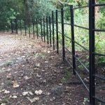 Black bespoke railings alongside a public walkway in a rural area.