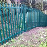 Green steel palisade fencing providing security for a private area in Birmingham.