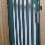 Green steel palisade gate securing a school yard.