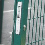 Green wire mesh gate with secure locking system.