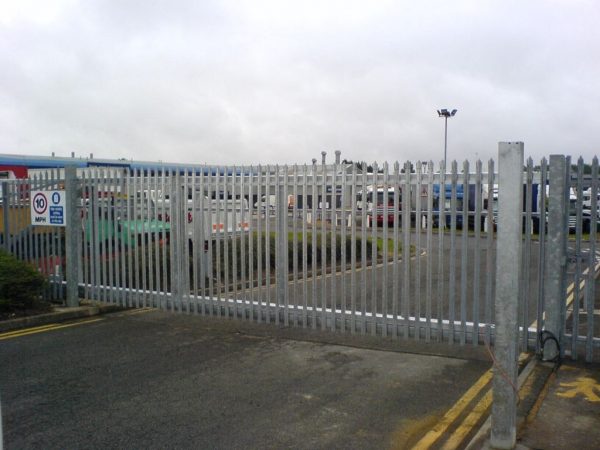 Steel palisade gates gate securing large vehicles in yard. These commercial gates are great for securing industrial spaces.