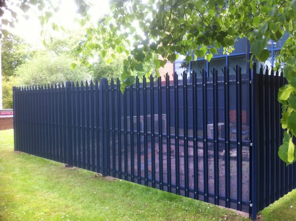 Blue steel palisade fencing surrounding industrial supplies.