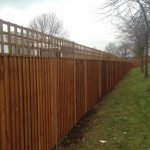 A large wooden fence in an open area. The fence has t type timber trellis fencing panels.