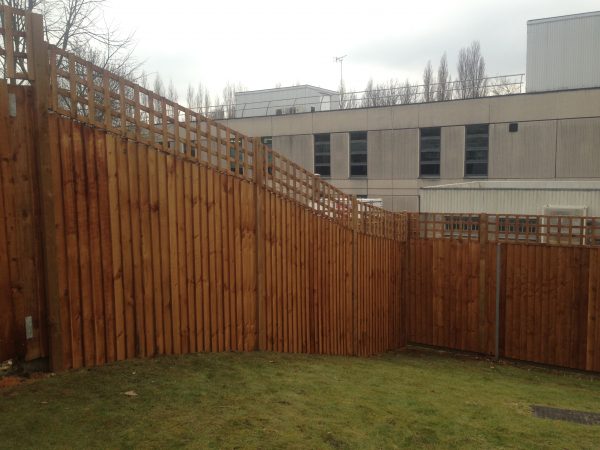 A large open space surrounded by a wooden fence. The fence has t type timber trellis fencing panels.