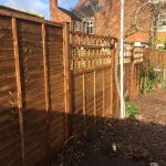 Wooden fence with v type fence panels double framed, horizontally overlapped with bevelled capping.