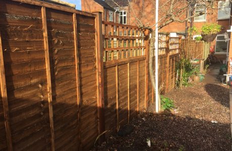 Wooden fence with v type fence panels double framed, horizontally overlapped with bevelled capping.