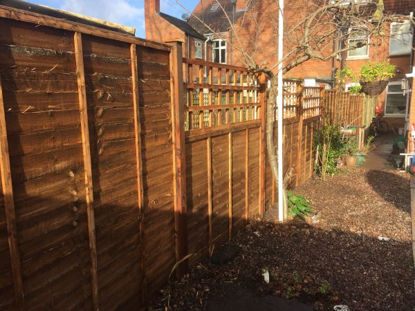 Wooden fence with v type fence panels double framed, horizontally overlapped with bevelled capping.