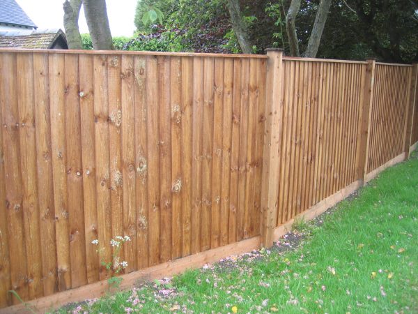 Pressure treated timber posts supporting a wooden fence in a empty garden.