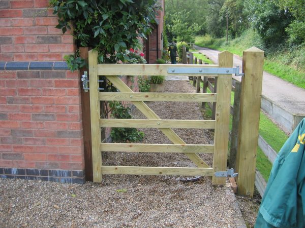 A five bar field gate securing a private property. The field gate is being supported by timber gate posts.