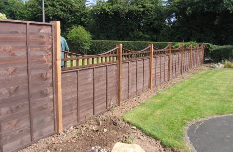 A large garden with a wooden fence. The fence has z type timber panels double framed, horizontally overlapped with bevelled capping.