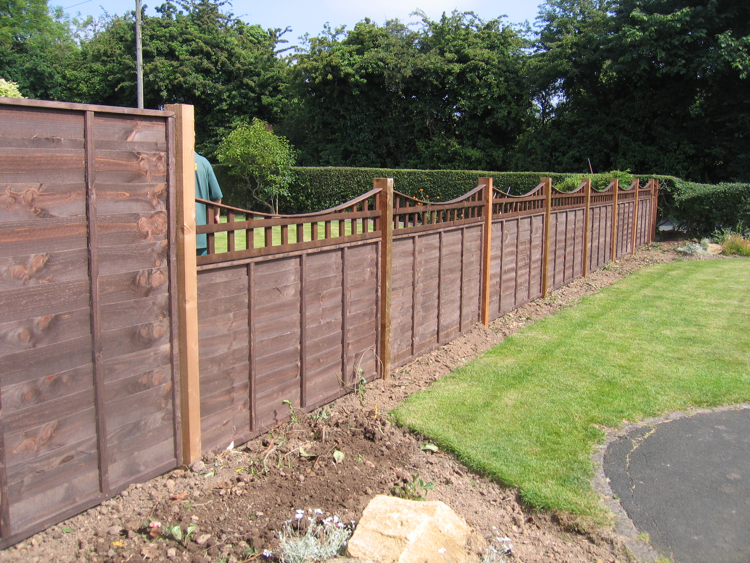 A large garden with a wooden fence. The fence has z type timber panels double framed, horizontally overlapped with bevelled capping.
