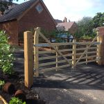 Houses with a long drive. The drive includes a field gate to protect the properties. The gate has supporting timber posts.