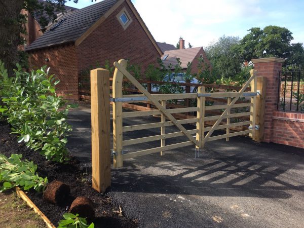 Houses with a long drive. The drive includes a field gate to protect the properties. The gate has supporting timber posts.