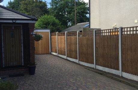 A house and garden with a wooden fence around the perimeter. The fence has v type close board fence panels.