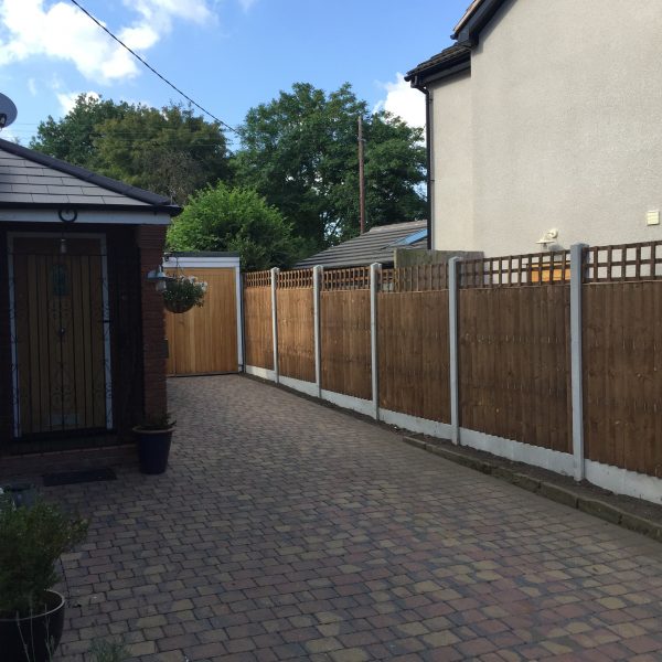 A house and garden with a wooden fence around the perimeter. The fence has v type close board fence panels.