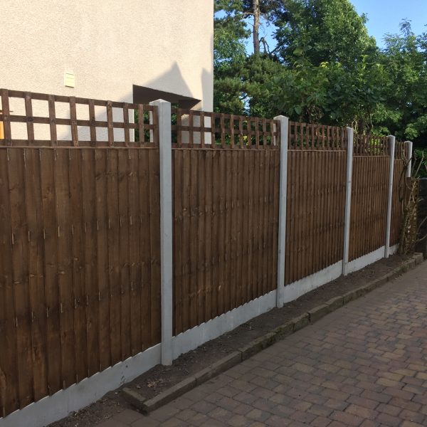 A wooden fence in a garden yard. The fence is v type fence with close board fence panels.