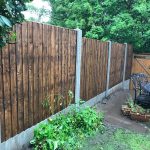 A garden yard with a wooden fence and a steel table. The fence has v type close board fence panels.